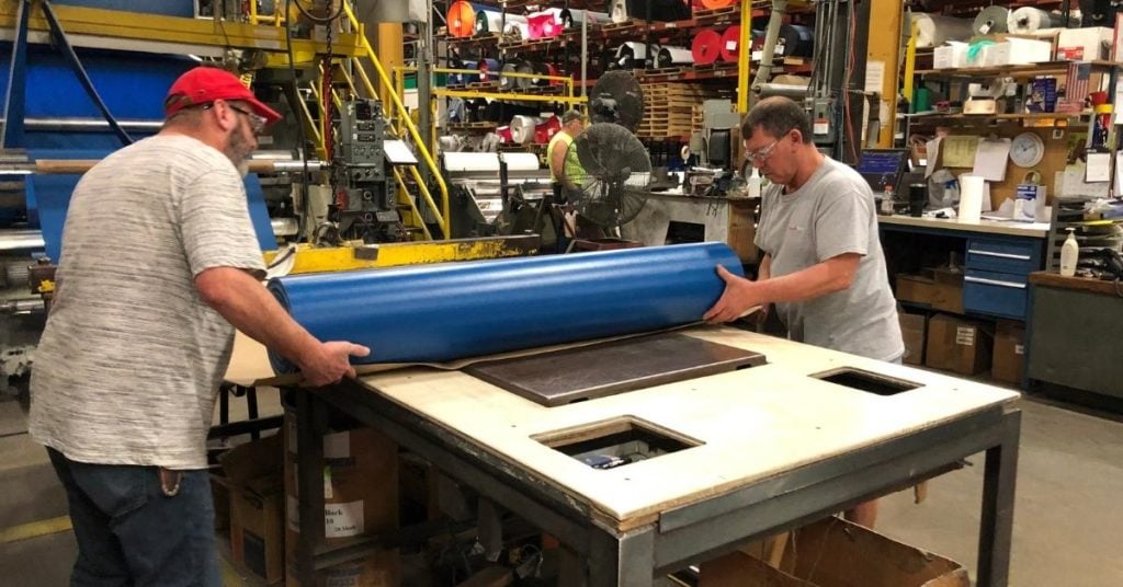 Two staff members in the Snyder Manufacturing plant preparing to wrap a roll of industrial fabric